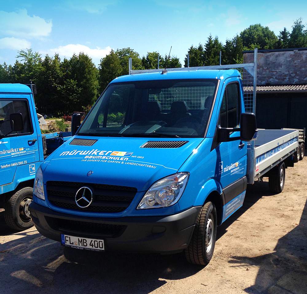 En blå lastbil med lad parkeret på en grusvej.