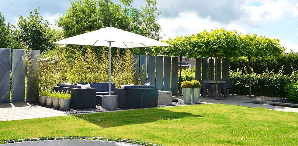 Eine Holzterrasse mit einem Tisch und Stühlen unter einem großen Sonnenschirm.